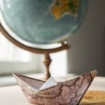 Paper boat with map near globe